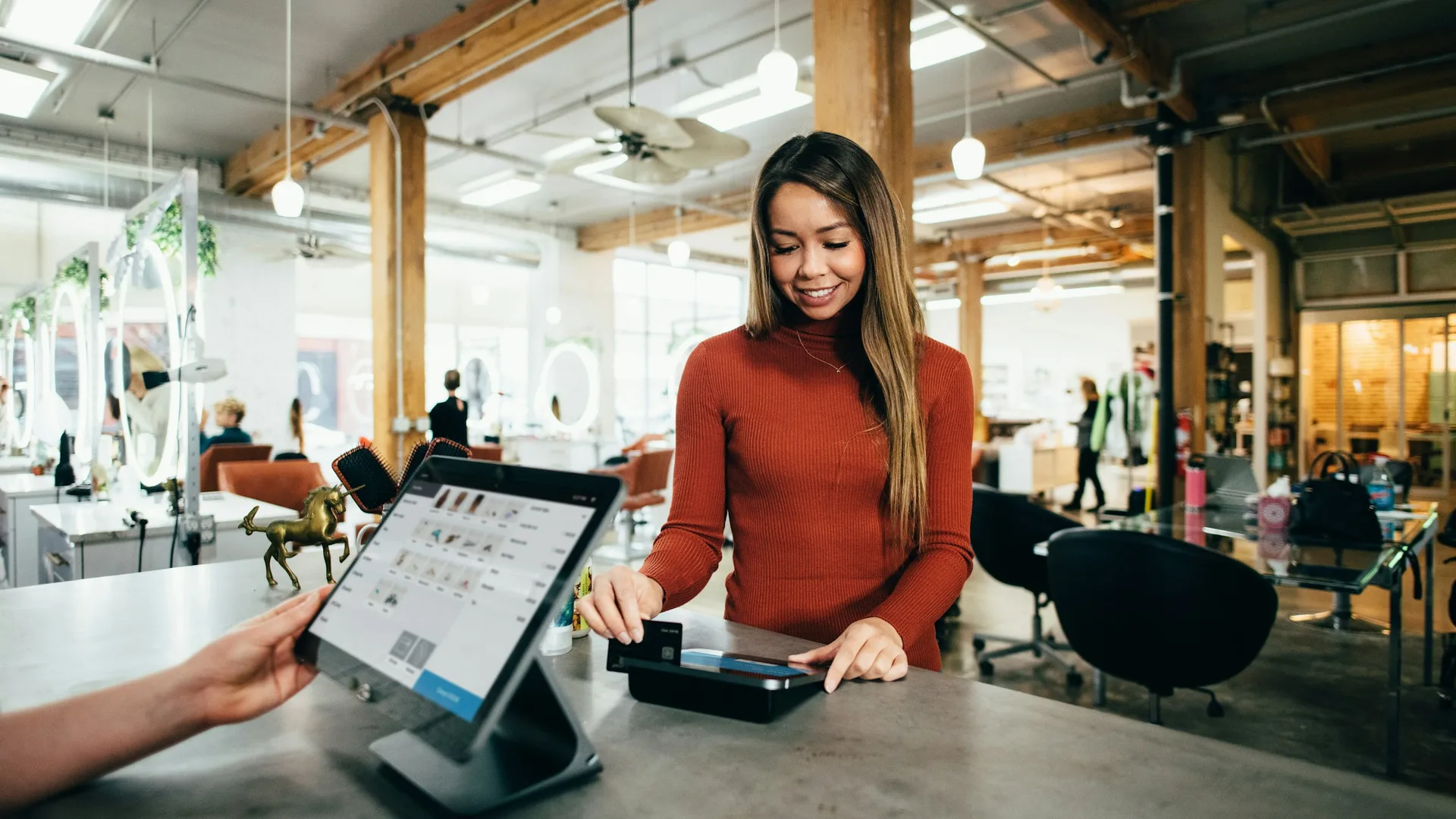 Salon owner taking a card payment at the counter in a working studio