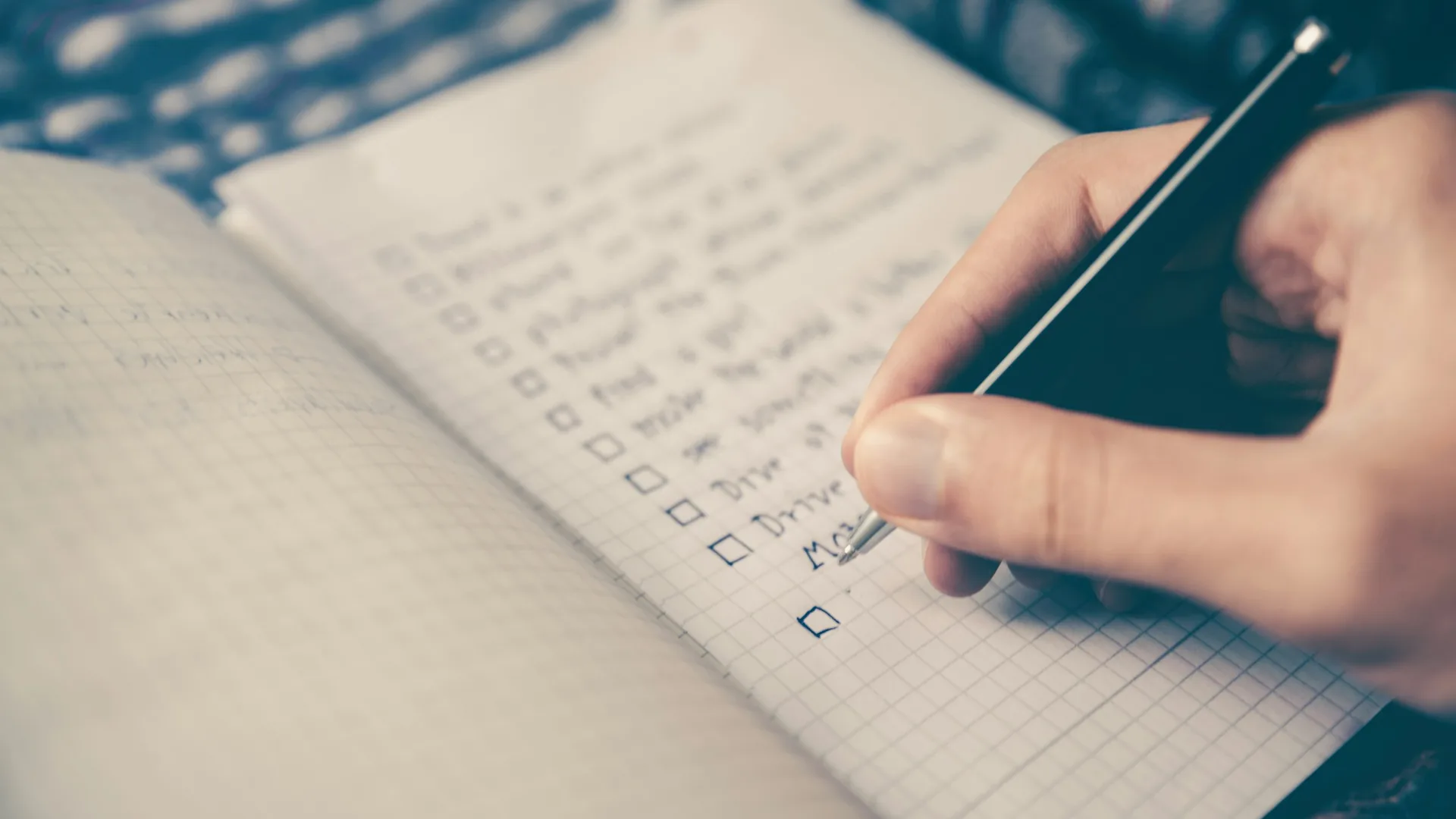 Hand checking boxes on a handwritten list in a notebook