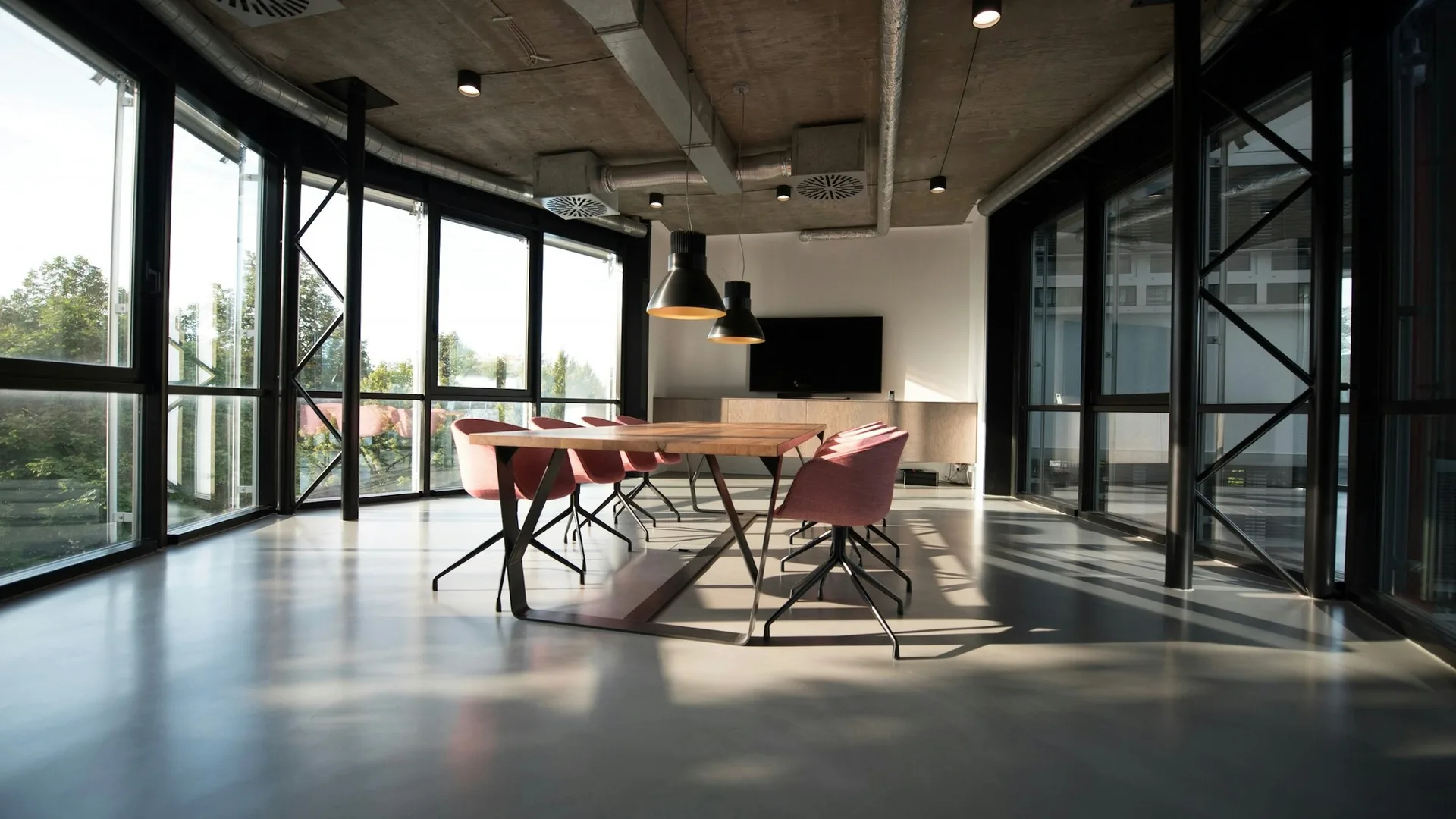 Empty glass-walled meeting room with a long table and pink chairs, a more operational office than a kitchen-table spreadsheet