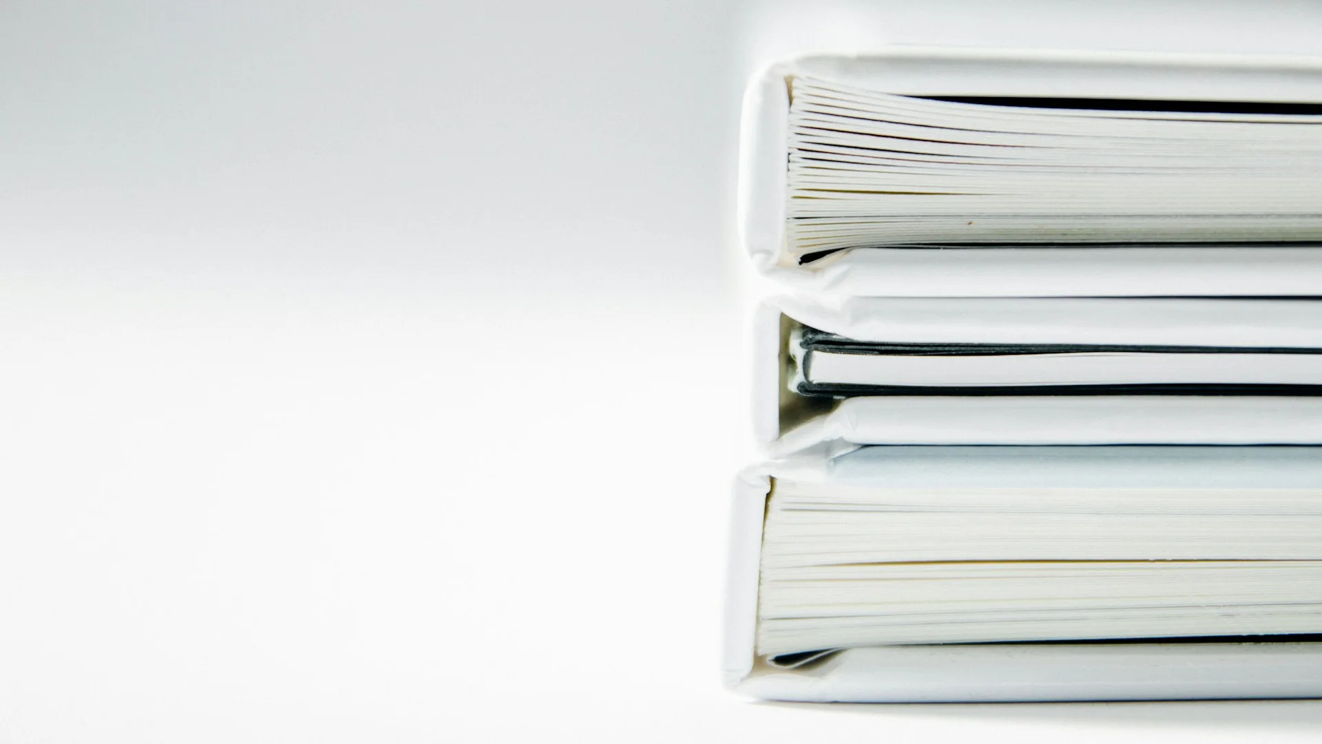 Stack of white binders lined up on a desk